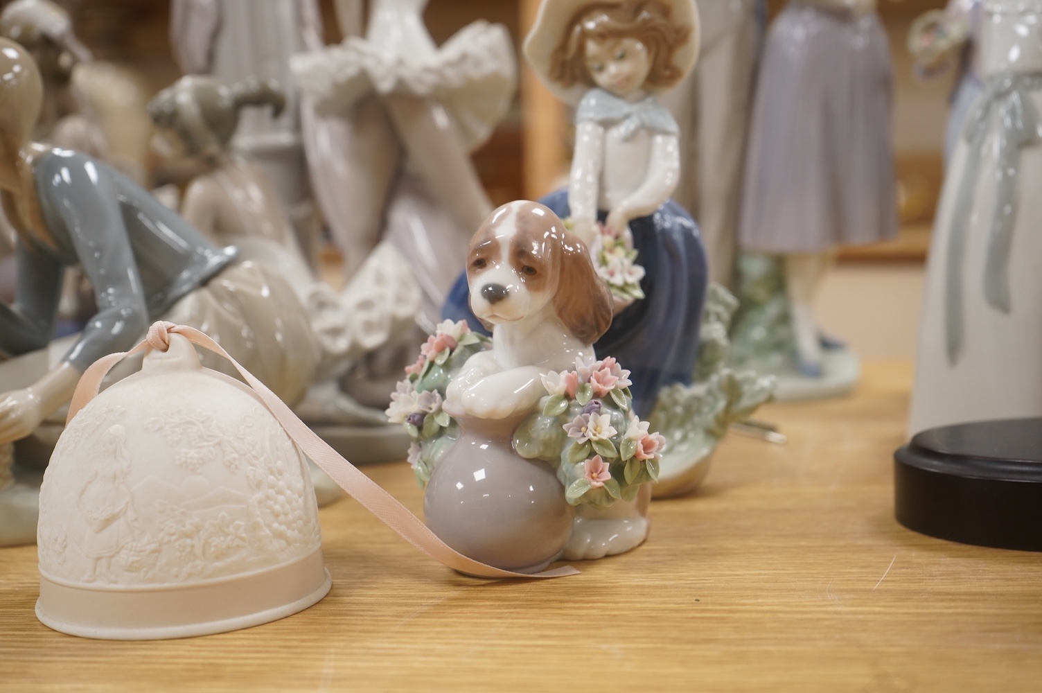 A large Lladro figure group of three ballet dancers by a tall floral column and eight other Lladro figures including a model of a bell. Tallest figure group 45cm high. Condition - golfer group, golf clubs broken.